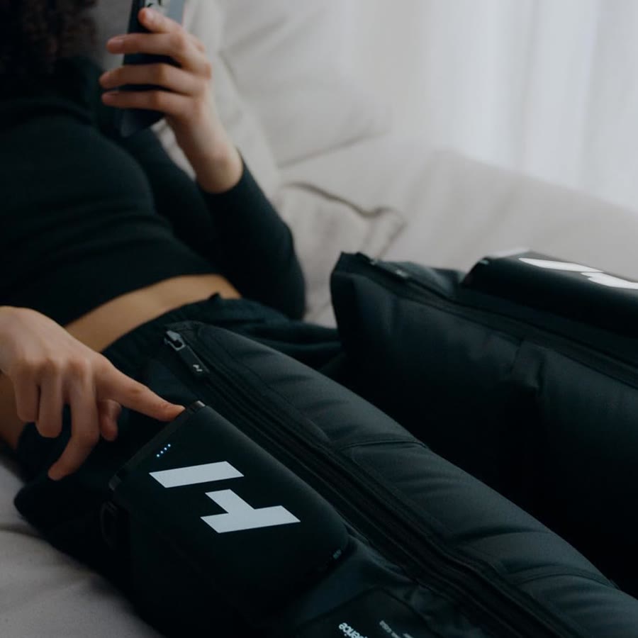 A patient lying back wearing Hyperice Normatec Elite leg boots