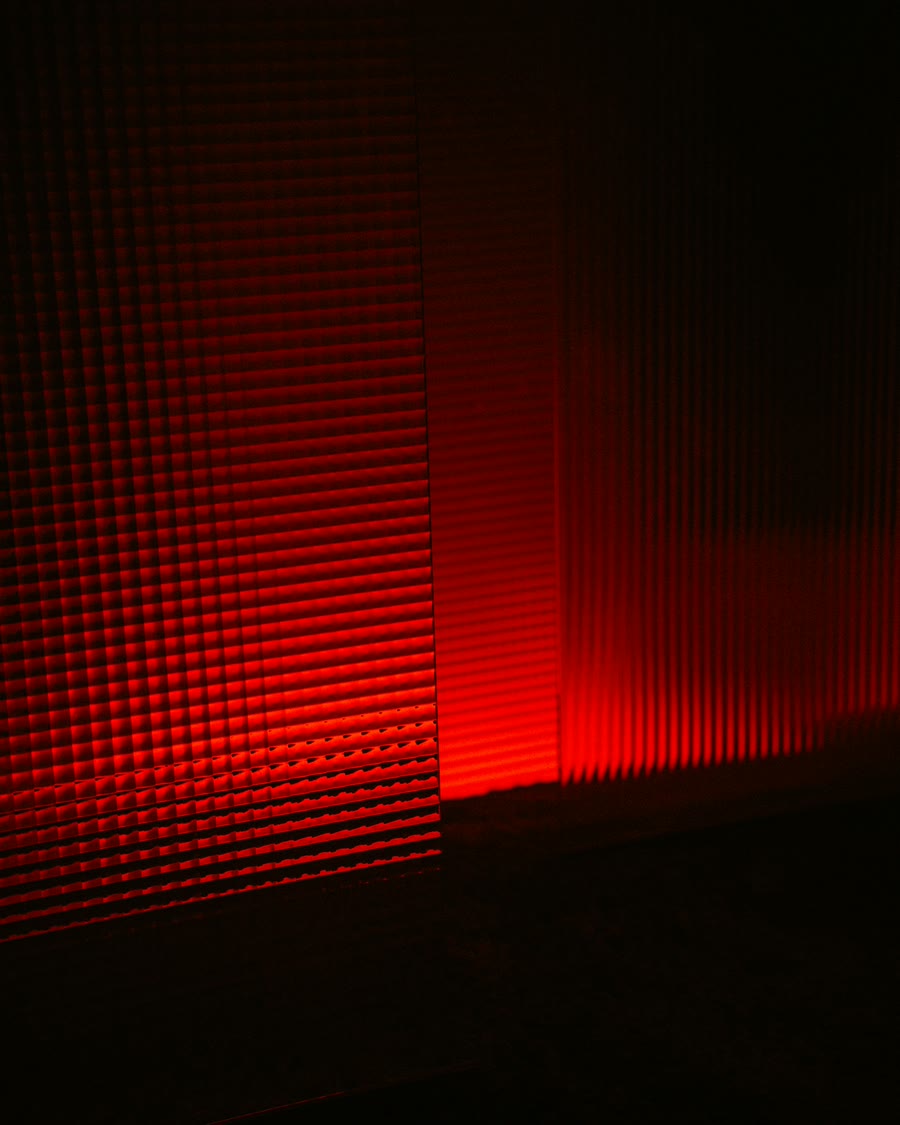 A red light therapy panel glowing in a dark room